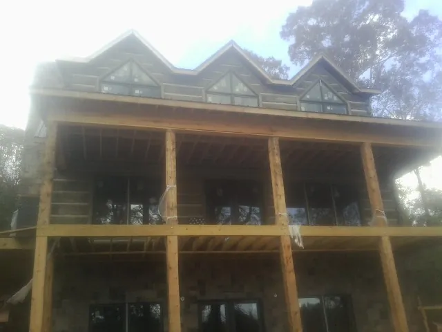 Dormers and porch framing on a large log home under construction — Roof Coating work by our crew in Fellsmere
