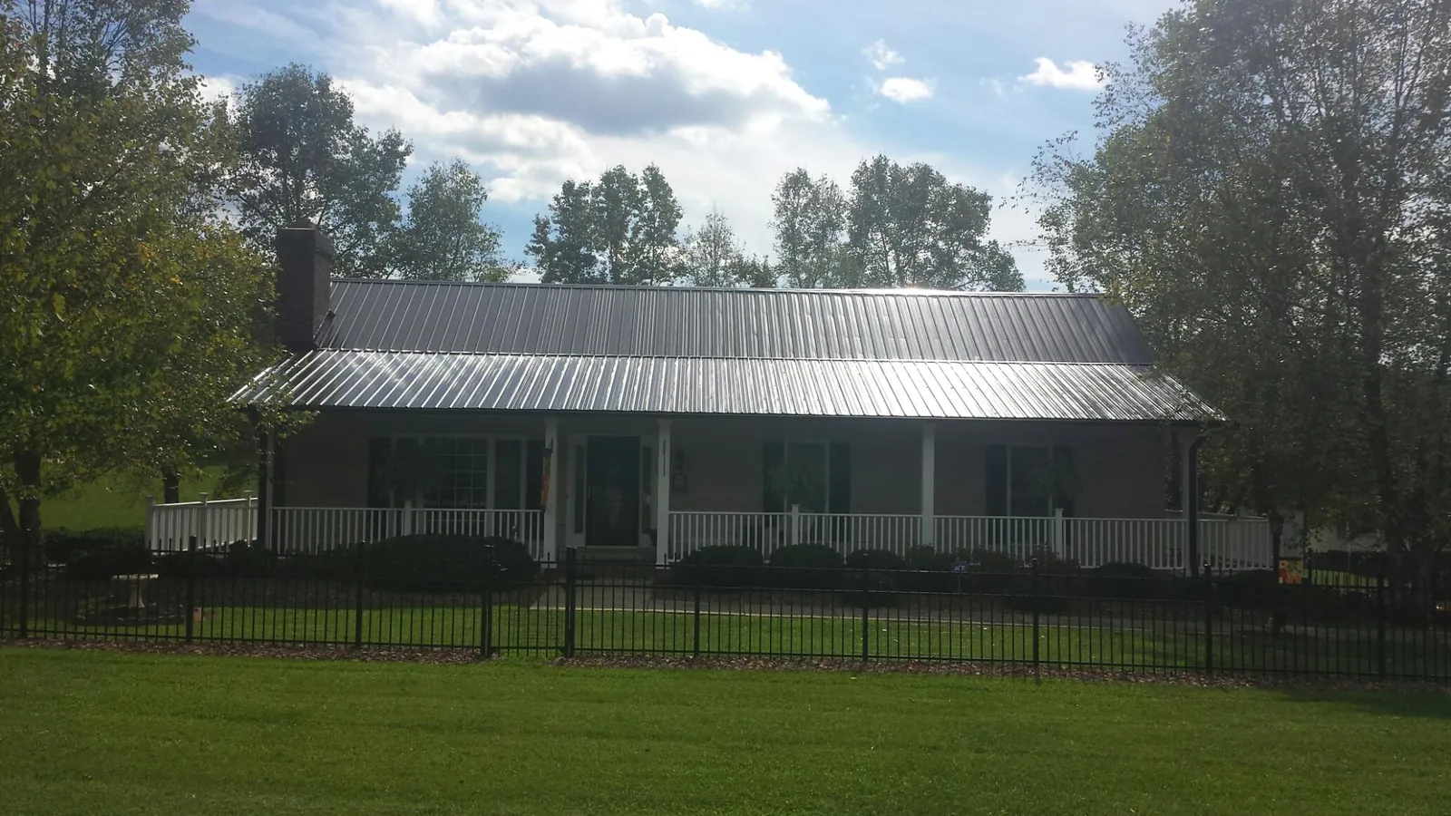 Gray metal roof on a brick ranch with a full width front porch — Gutter Guard Installation work by our crew in Fellsmere
