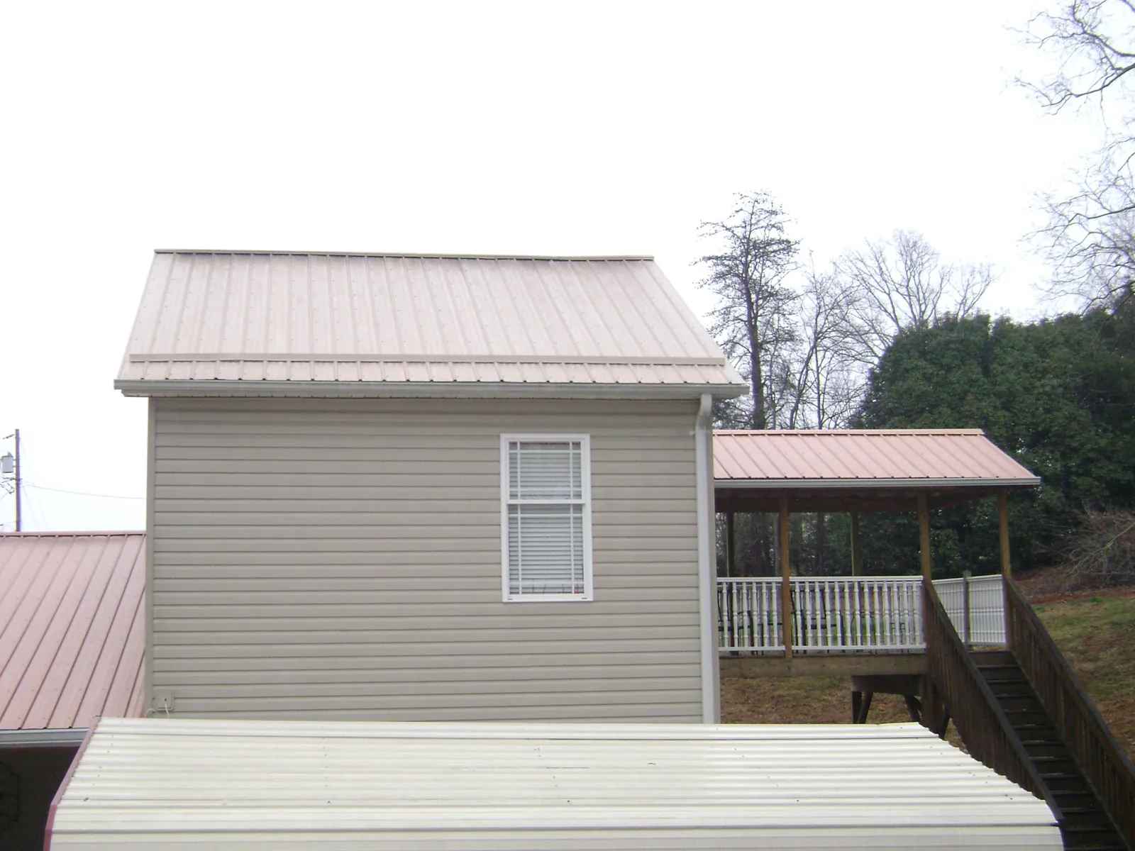 Tan metal roofs on a two story addition and attached porch, from a Roof Replacement job in Fellsmere